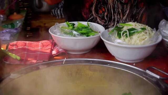 the seller put the noodles to be boiled into the boiling pot. street food named "Mie Ayam". Indonesian chicken noodles. Selective focus. 4K videos.