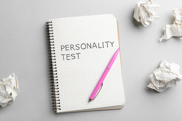 Notebook with text Personality Test, pen and crumpled sheets of paper on light background, flat lay