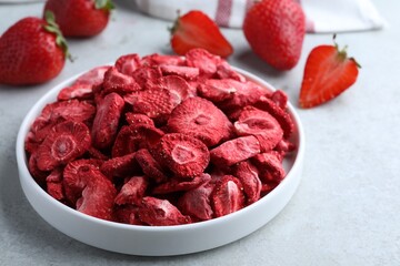 Freeze dried and fresh strawberries on light grey table, closeup