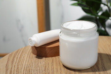 Jar and tube of hand cream on wooden table indoors, space for text
