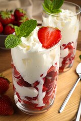 Delicious strawberries with whipped cream served on wooden table, closeup