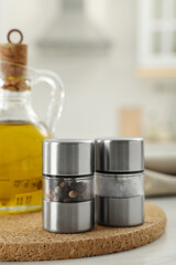 Salt and pepper mills with bottle of oil on table in kitchen