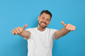 Man showing thumbs up on light blue background