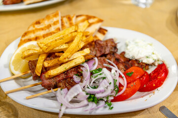 Fried meat souvlaki, fresh vegetables, pita bread, tzatziki sauce and french fries, traditional greek food served in cafe
