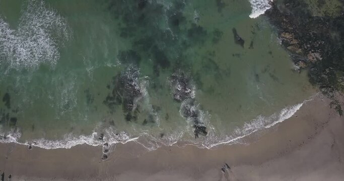 small waves hitting the rocks on the beach. green ocean.