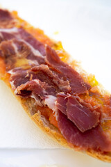Breakfast toast of cured ham with the bread served on a white plate on a white table. Close-up