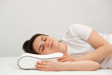 A woman sleeps on an orthopedic pillow made of memory foam, lying on a bed. The correct pillow for...