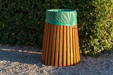 wooden trash can with a green bag on the background of green foliage on the beach of the resort...
