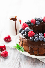 Homemade Vegan Chocolate Cake with Fresh Berries on White Table.