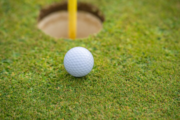 Close up of golf ball next to hole.