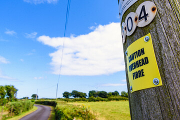 Sign on a wooden telephone pole warning people that the pole is carrying fibre optic cable.