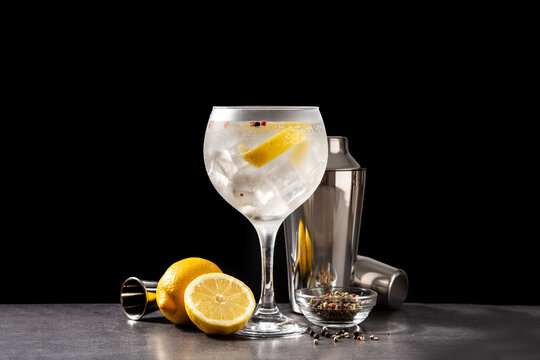 Gin tonic cocktail drink into a glass on black background