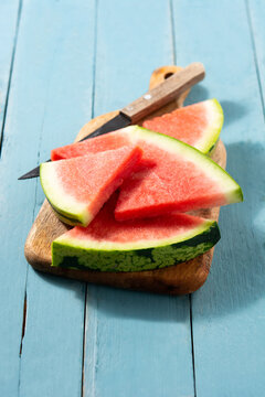 Fresh watermelon slices on cutting board and blue wooden table background