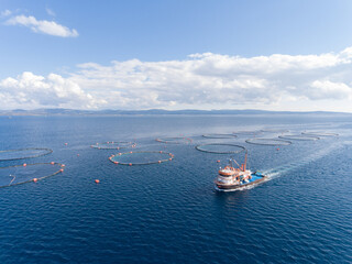 Aerial view of a fishing boat in the sea. Circle fishing farms at background