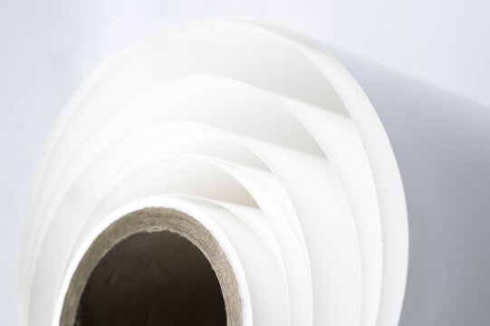 White polygraph paper on a cardboard core. A bundle of leftover paper in a printing house. Material for the printing industry. Selective focus