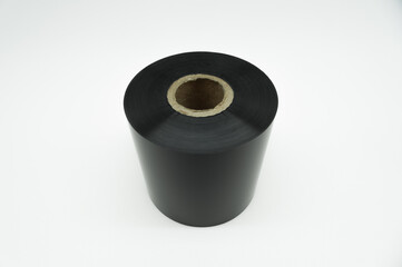 Black roll wax ribbon for thermal transfer on cardboard core for a special barcode printer. Consumables and auxiliary materials for barcode printing. TTR ribbon. Selective focus.