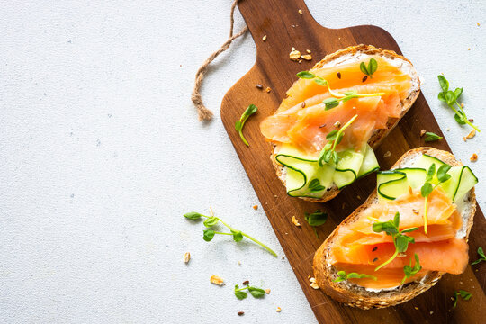 Open sandwich with cream cheese, salmon and cucumber. Top view at white table.