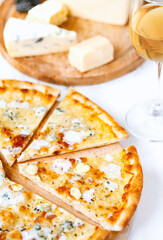 Pizza quattro formaggi on a wooden board .four cheese pizza and fresh ingredients for a four cheeses Italian pizza on a white wooden desk .