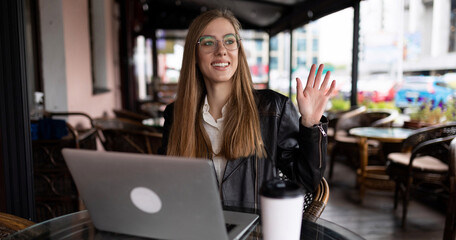 young woman student working online in a cafe on a laptop with a cup of coffee