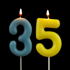 Burning colorful birthday candles isolated on black background, number 35