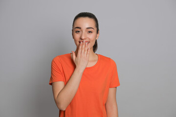 Beautiful young woman laughing on grey background. Funny joke