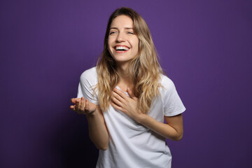 Cheerful young woman laughing on violet background