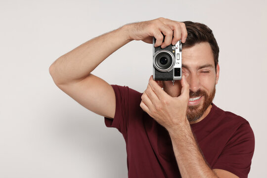 Man with camera taking photo on white background. Interesting hobby