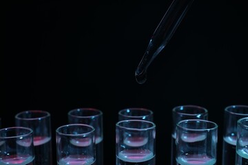 Dripping reagent into test tube on black background, closeup. Laboratory analysis