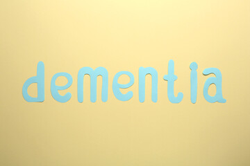 Word Dementia made of paper letters on beige background, flat lay