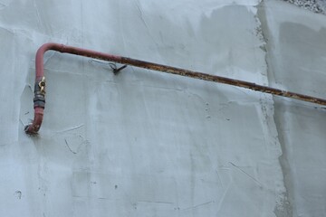 Rusty gas pipe at light wall outdoors, low angle view