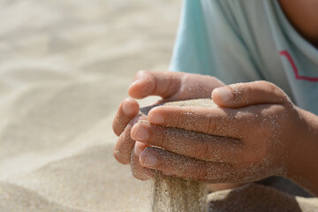Child pouring sand from hands outdoors, closeup with space for text. Fleeting time concept