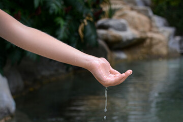 Kid pouring water from hand in pond, closeup