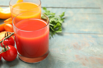 Delicious vegetable juices and fresh ingredients on blue wooden table, closeup. Space for text