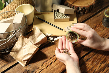 Woman with vegetable seeds at wooden table, closeup