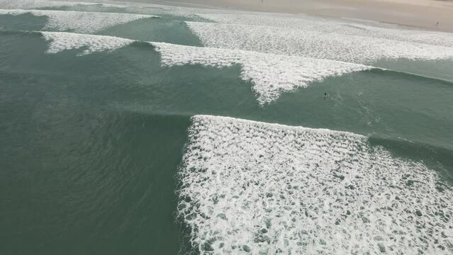 Surfers surf on waves with surfboards at the Pointe de la Torche in Brittany