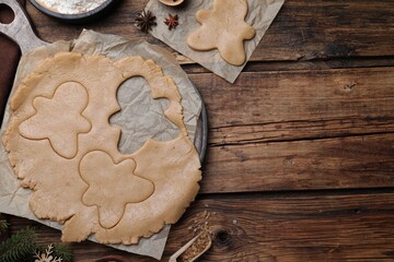 Flat lay composition with homemade gingerbread man cookies on wooden table, space for text
