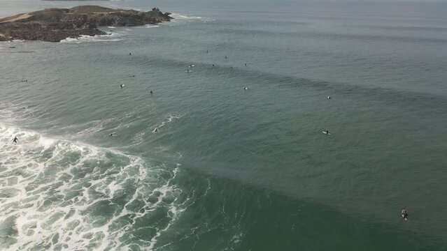 Surfers surf on waves with surfboards at the Pointe de la Torche in Brittany