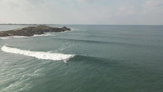 Surfers surf on waves with surfboards at the Pointe de la Torche in Brittany
