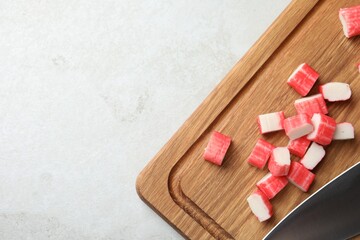 Board with cut crab sticks on light table, top view. Space for text © New Africa