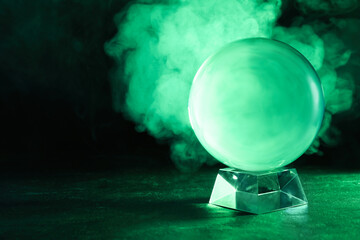 Crystal ball on table and smoke against dark background, space for text. Predictions of future