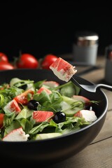 Delicious crab stick salad in bowl on wooden table, closeup