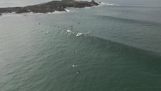 Surfers surf on waves with surfboards at the Pointe de la Torche in Brittany