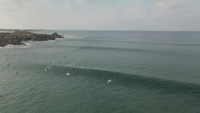 Surfers surf on waves with surfboards at the Pointe de la Torche in Brittany