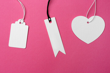 Set of different tags with space for text on pink background, flat lay