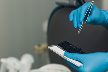 the orthodontist takes the button for braces with forceps.