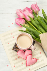 Romantic flat lay composition with a cup of coffee, soft felt hearts, and fresh tulips