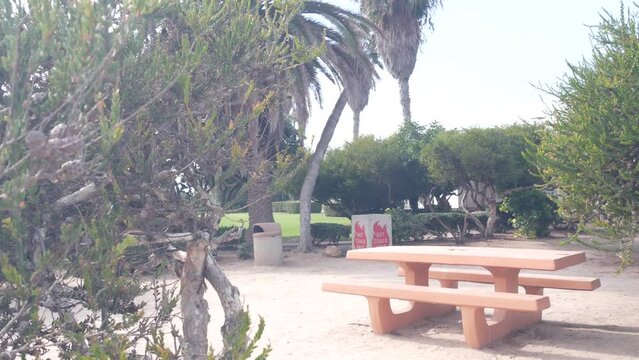 Picnic area in public park, La Jolla Cove, California coast, USA. Recreation place for barbecue. Bbq hot coals only cement dumpster. Table and bench for barbeque, grill and rest alfresco. Fire safety.