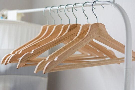 Lots of wooden hangers on an empty white rail. Concept: cluttering Organization of storage space. Close up view of empty wooden hangers on rack isolated on white 