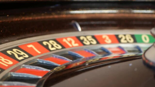 Ball on wooden french roulette table in casino. Wheel spinning, turning or rotating. Odd and even numbers, black, red and zero sectors. Bets in game of chance. Money playing, gambling or risky betting