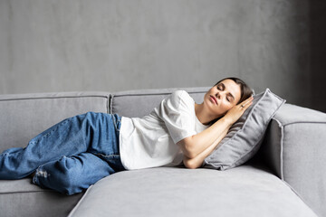 Young sleepy woman falls down on sofa. Apathetic tired lazy lady sleeping on couch at home.
